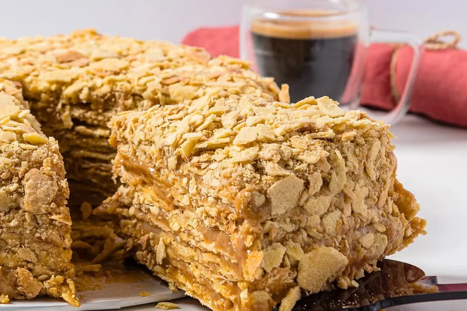 Torta de mil hojas con una porción servida junto a un espresso sobre la mesa