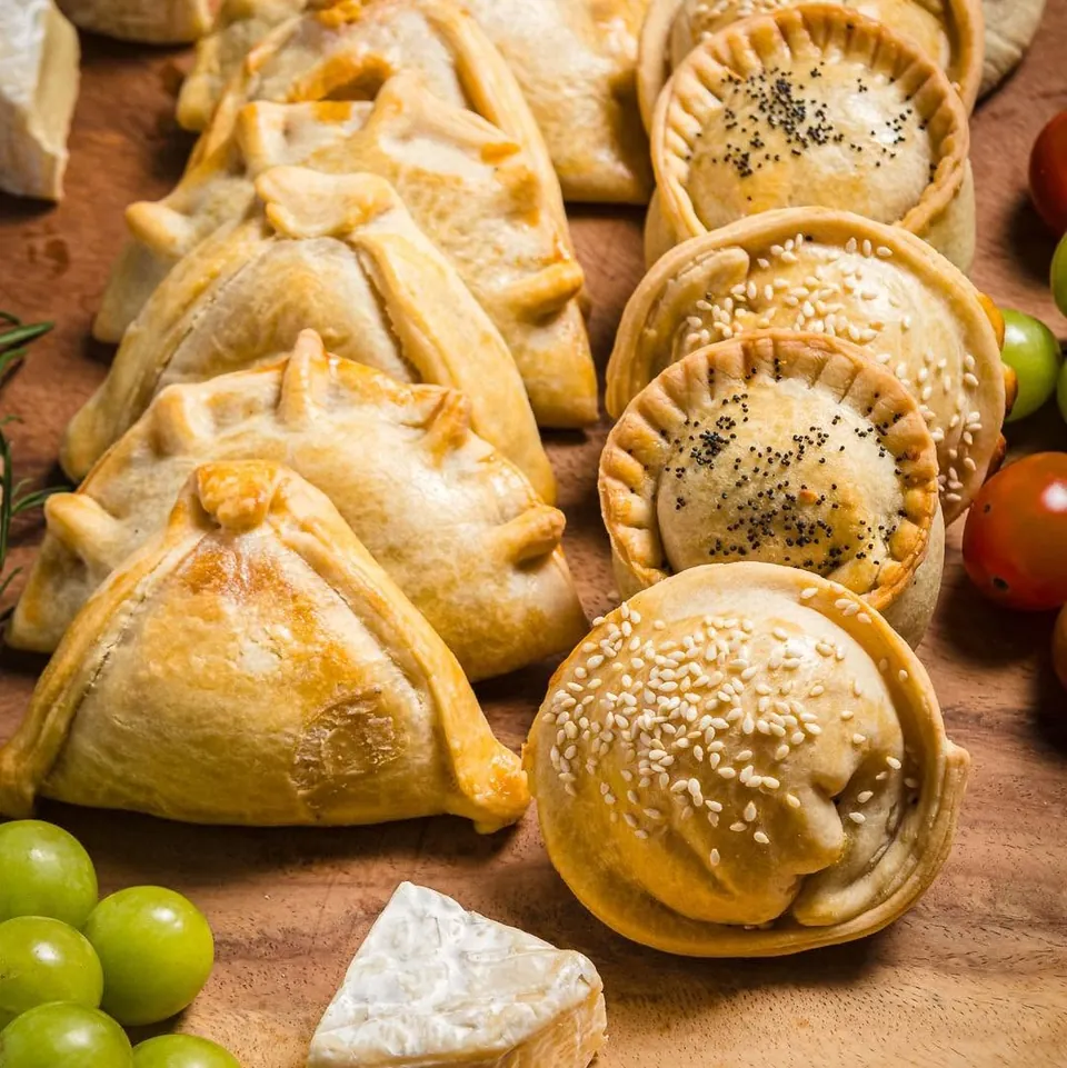 Empanadas y empanaditas horneadas sobre una tabla de madera
